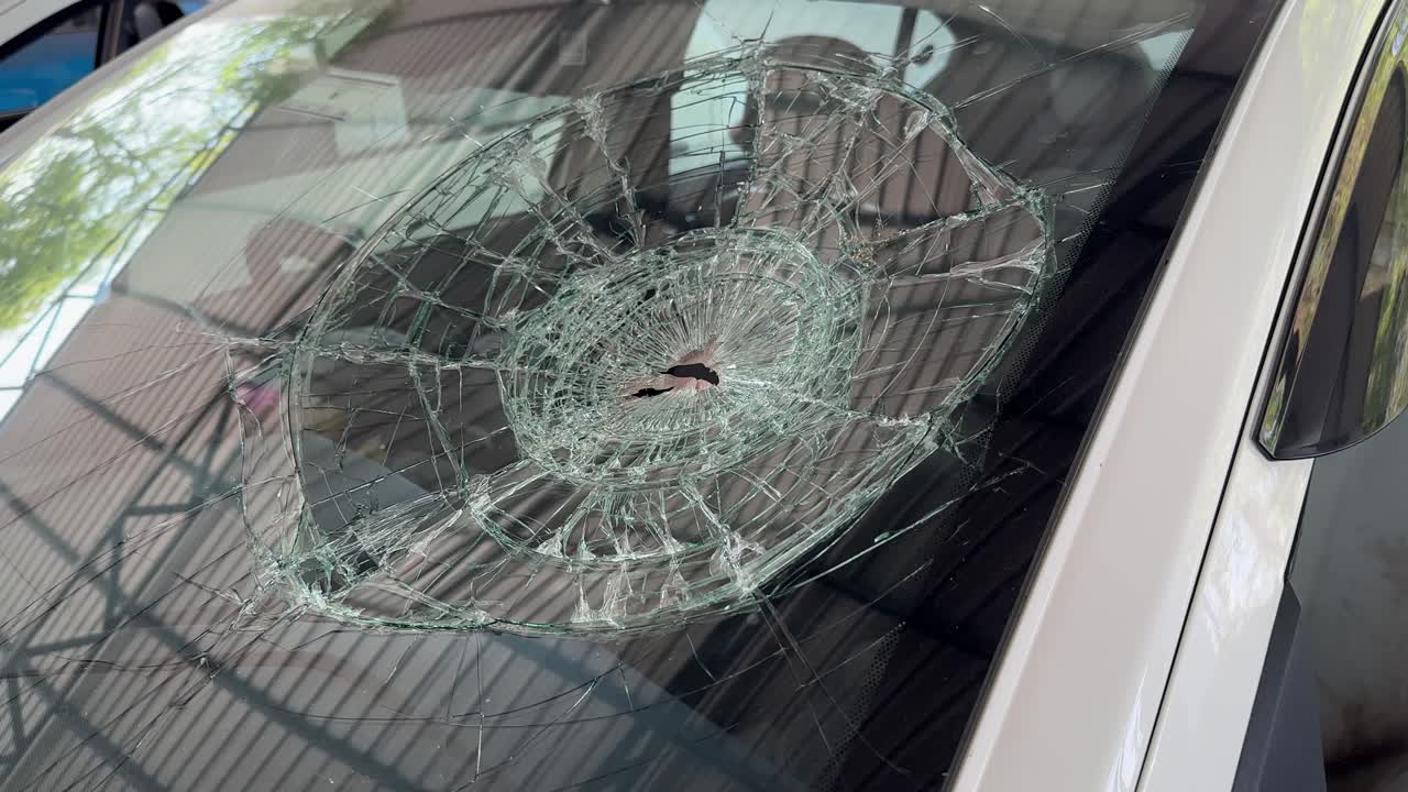 camera spinning around a broken windshield of a car by bullet or stone