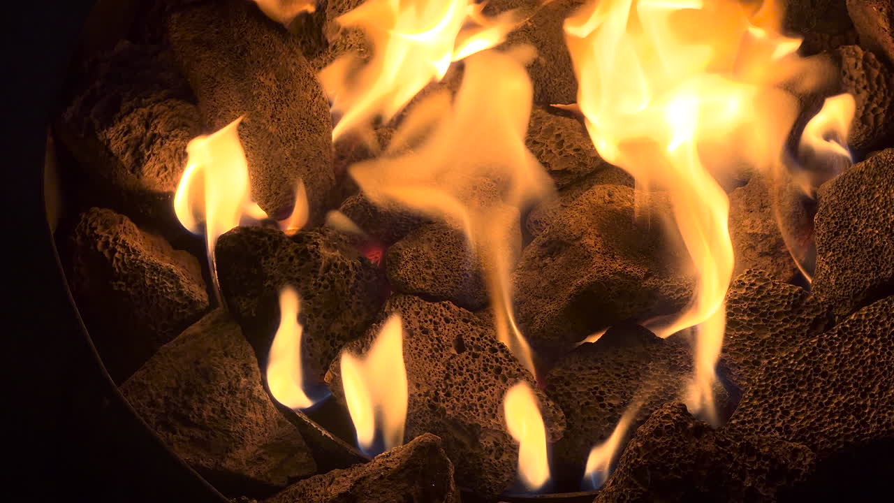 Flames and lava rocks from a propone portable fire pit.