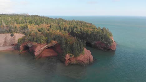 slow aerial decent showcasing a stunning cliff with trees on it in st, martins, new brunswick