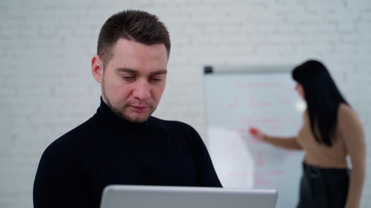 Man working with woman. Young businessman working against standing woman near board
