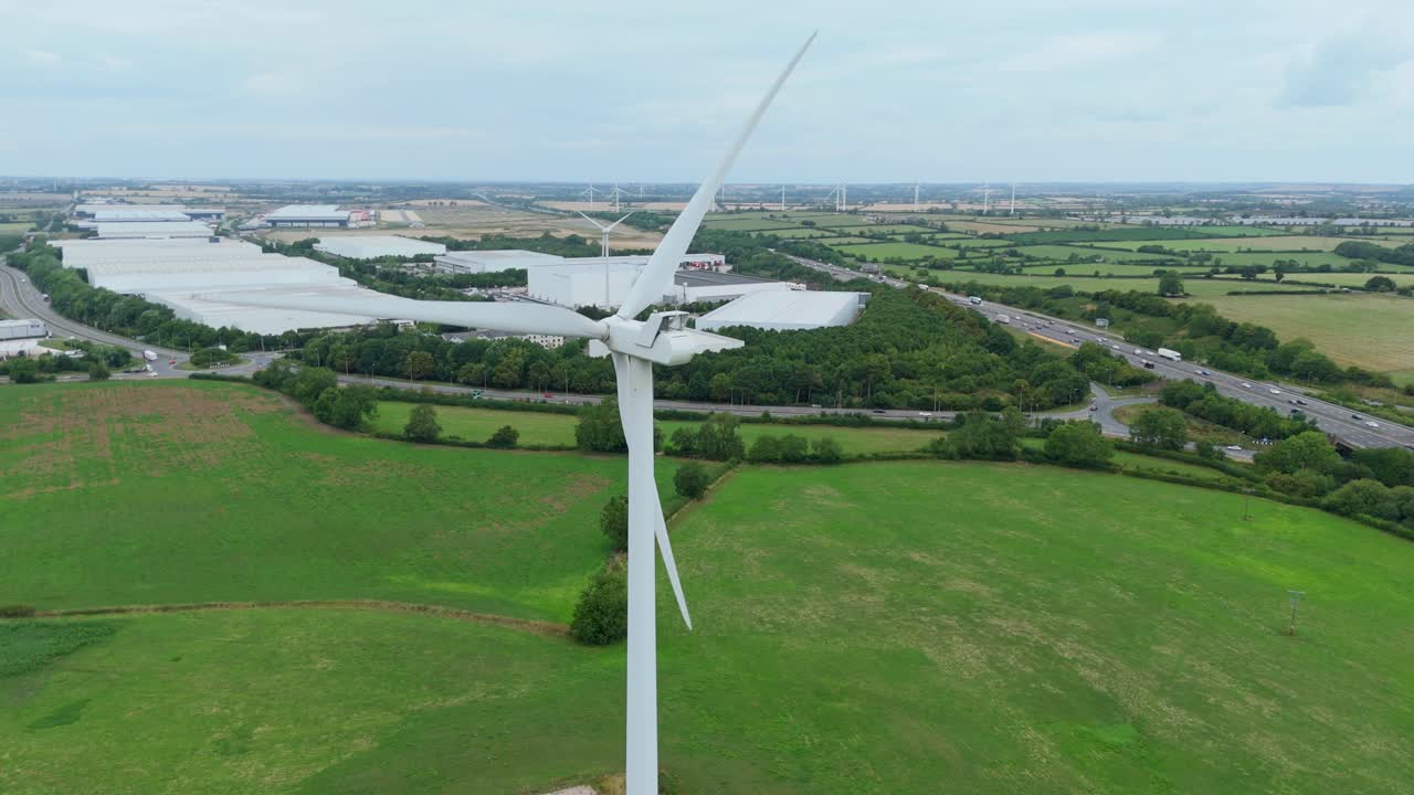 Cinematic drone close up aerial footage of wind turbines and mills with industrial warehouses and logistics hubs Lutterworth United Kingdom