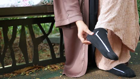 Young-women-feeling-pain-on-feet-sitting-on-a-park-bench-,