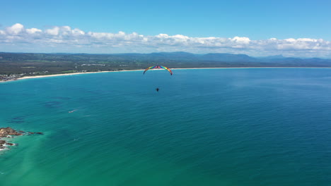 Disparo-De-Dron-De-4k-De-Ancho-De-Un-Hombre-Volando-En-Parapente-Sobre-El-Mar-Del-Océano-En-Byron-Bay,-Australia