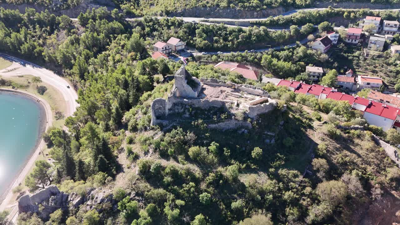 Drone circles around Kurjaković Fortress above Obrovac, revealing the green Zrmanja River and wide town views