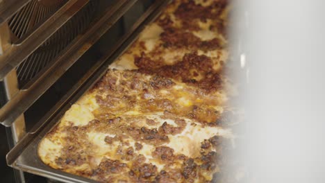 close-up view when a delicious baked bolognese lasagna taken out of the oven, italy.