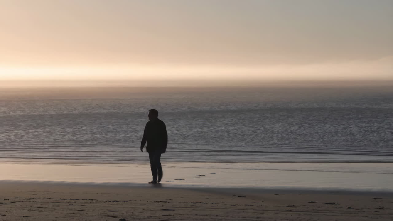 Solitary Figure Walking on a Misty Beach at Sunset
