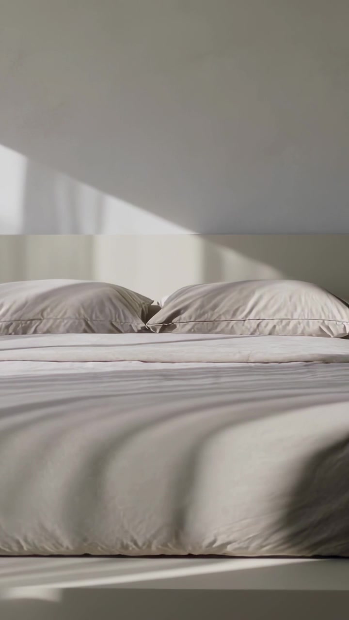 Vertical video: Moving sunlight across platform bed with two pillows in bedroom as sun shifts