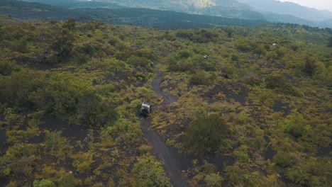 Drone-aerial-shot-of-cars-driving-in-a-volcanic-landscape-in-Guatemala