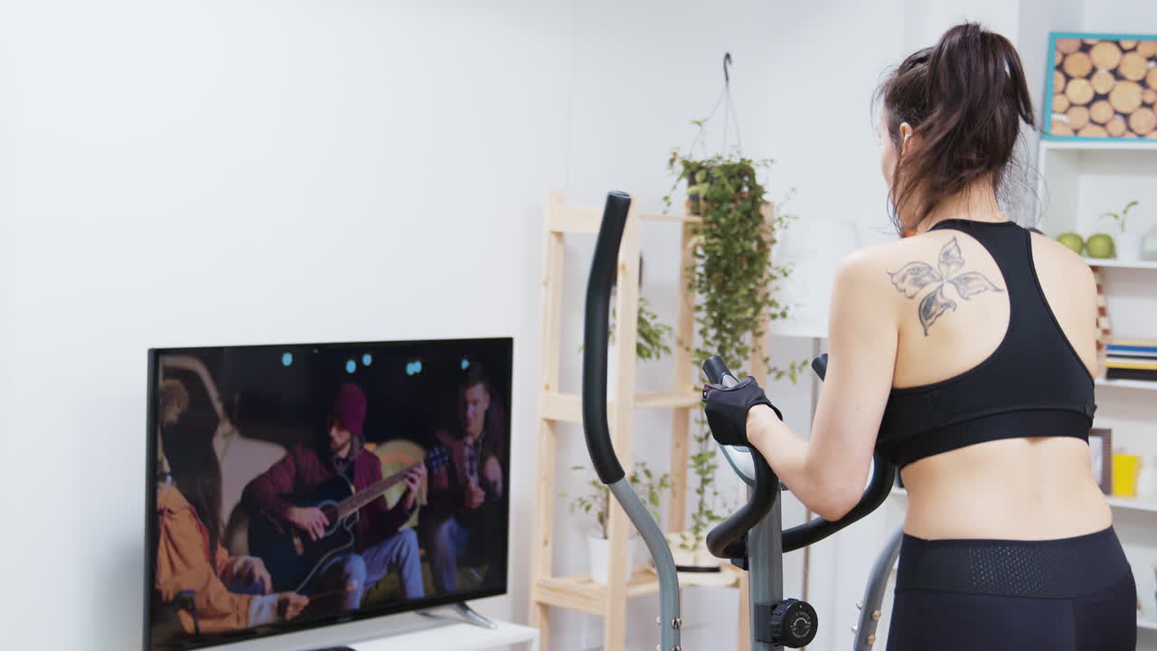 Woman exercising on elliptical while watching TV