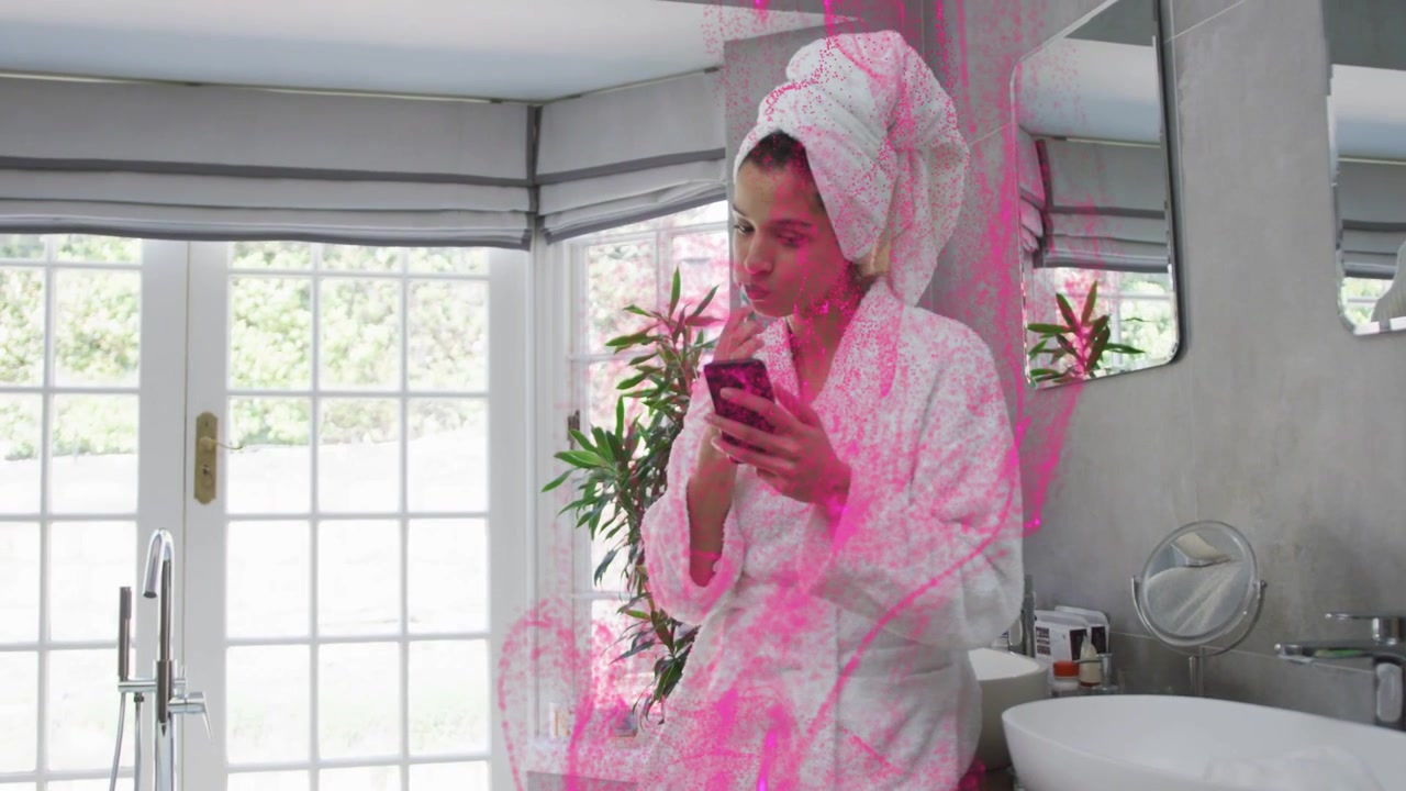 Woman leaning on vanity tapping phone using lip product, causing beauty pink smoke enveloping torso