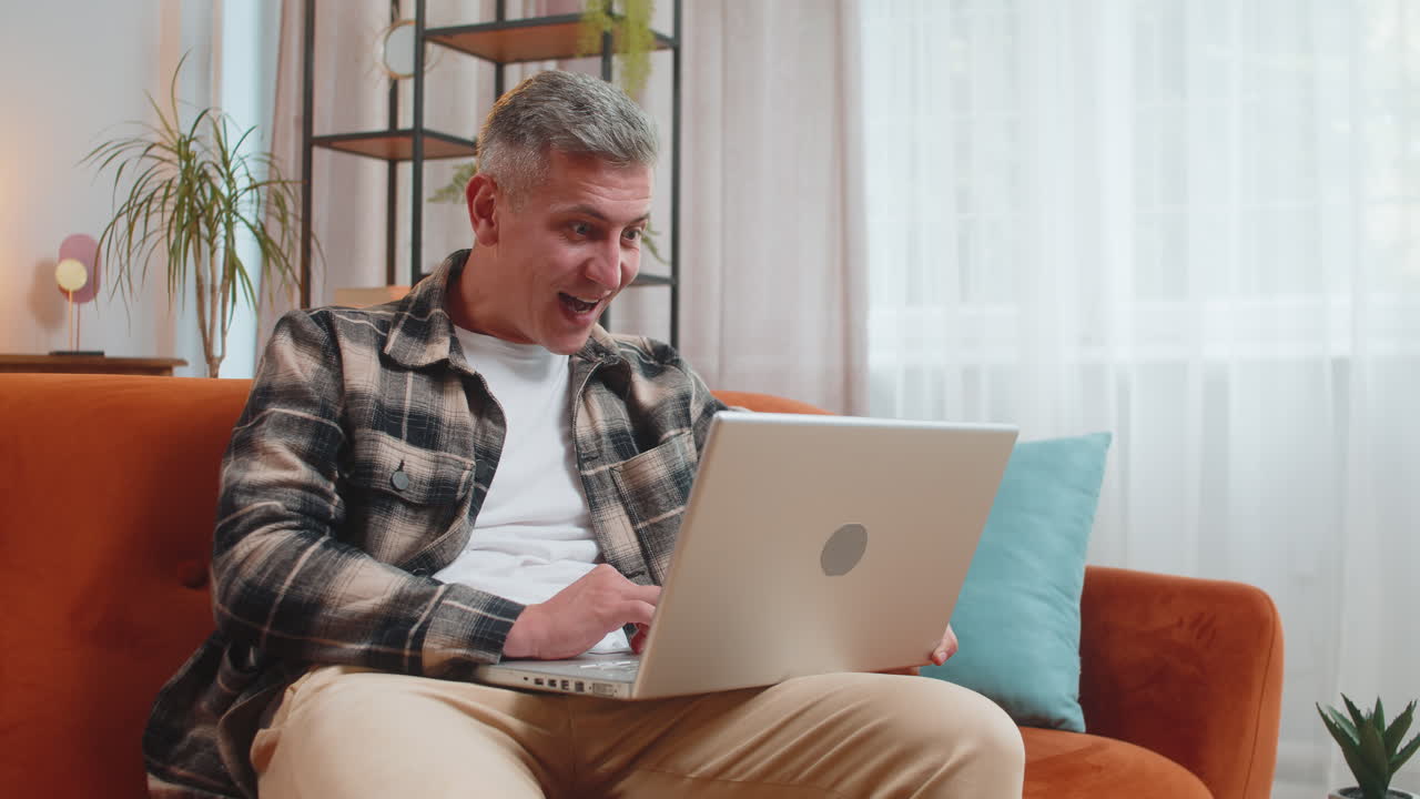 Amazed young man use laptop computer receive good news message shocked by victory celebrate win