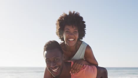 Portrait-of-smiling-african-american-couple-embracing-on-sunny-beach