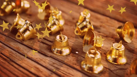 animation of stars flying over christmas bells decorations on wooden surface