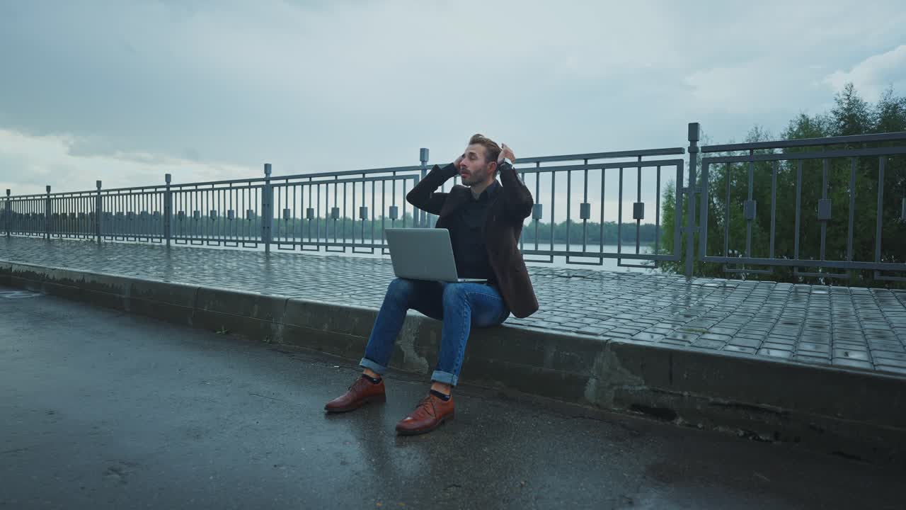 Man Stressed Outdoor Working on Laptop in the Rain