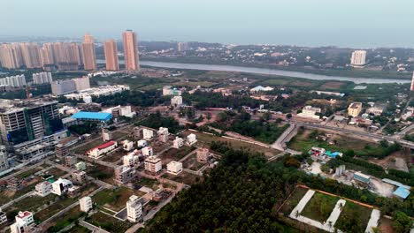 aerial view of chennai, india, showing high-rise buildings and low-rise residential areas. a river flows through the scene, with industrial structures also visible.