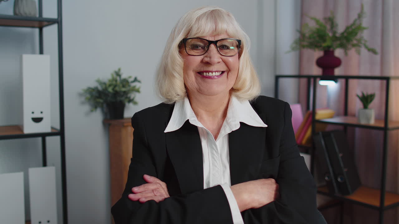 Cheerful senior mature business office woman wears glasses, formal suit, smiling, looking at camera