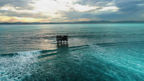 Aerial-dolly-to-judge-support-tower-on-stilts-at-Cloudbreak-Fiji-at-sunset