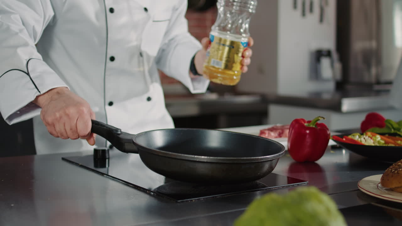Male chef pouring sunflower oil from bottle in pan on stove
