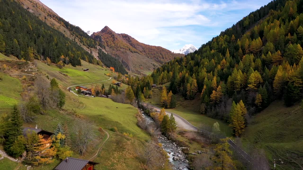 drone volando sobre el pueblo suizo en otoño: otoño con montañas y un río en el fondo