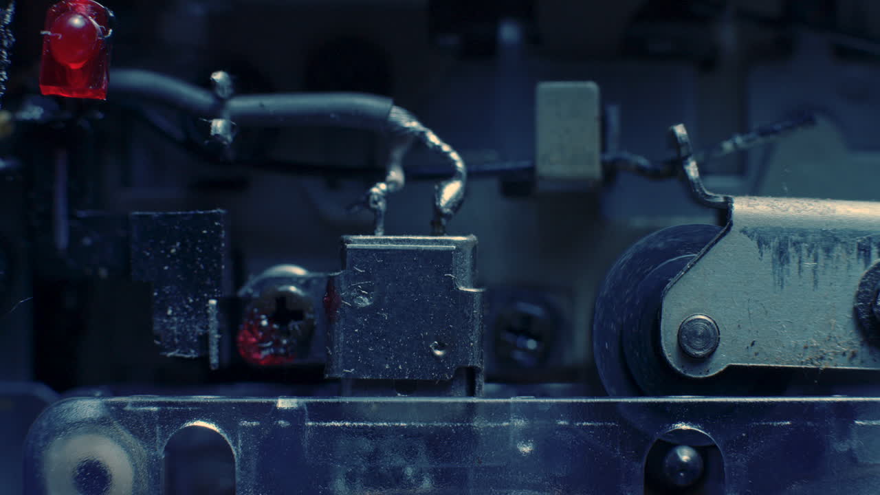 파란색 조명 아래 마이크로 카세트 레코더 내부에서 작동하는 재생 헤드 및 핀치 롤러의 클로즈업