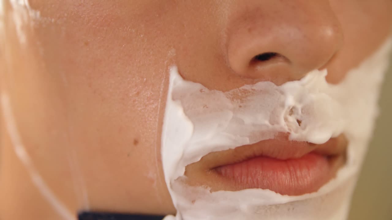 hombre afeitándose con una navaja en el baño en casa 4k