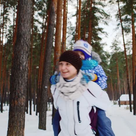 Active-Mom-Carrying-Daughter-Through-Snowy-Woodland