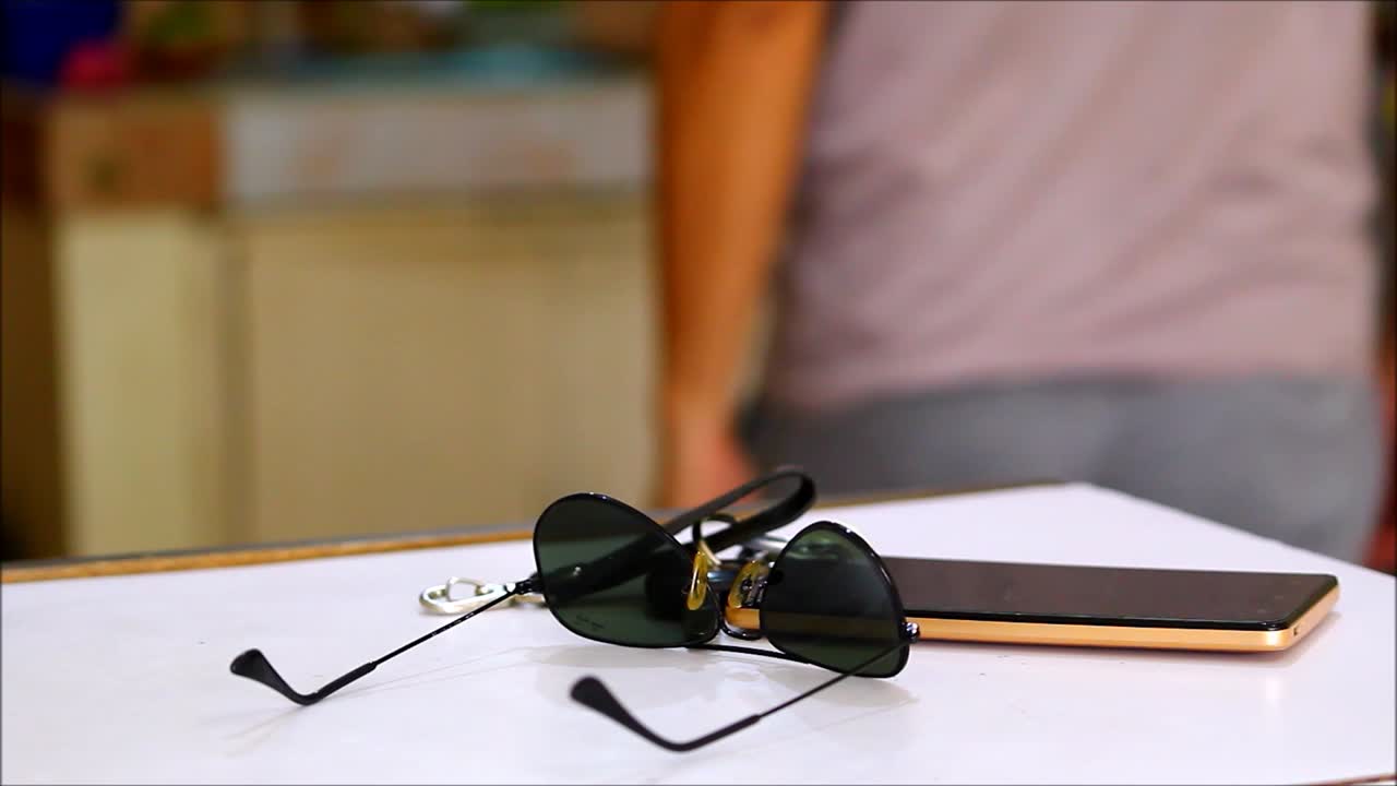 Video shot of a man putting down car keys, sunglasses and smartphone on a table