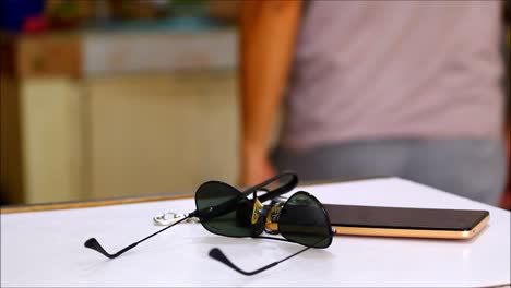 video shot of a man putting down car keys, sunglasses and smartphone on a table