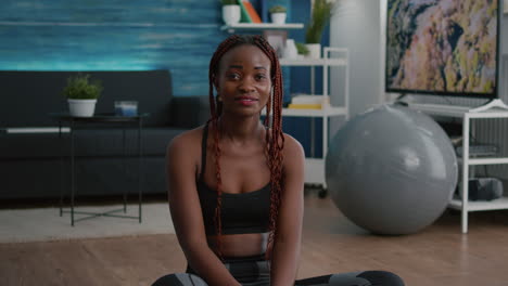 portrait of athlete fit woman looking into camera while sitting in lotus position