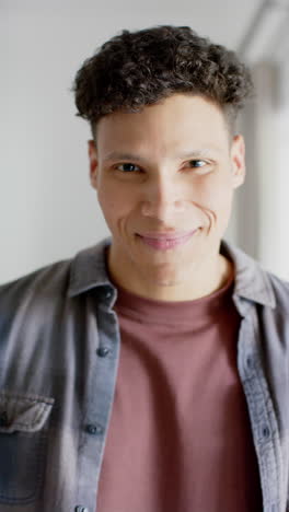 vertical video of portrait of happy biracial man at home, in slow motion