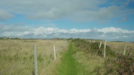 toma de paisaje de 4k de un camino peatonal entre campos, en la isla de portland, en dorset, inglaterra, en un hermoso día soleado