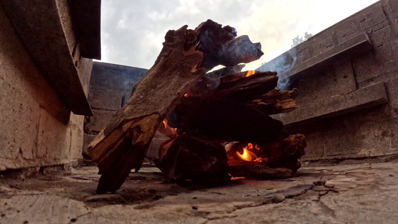 Timelapse of flame growing steadily in outdoor braai with glowing wooden embers