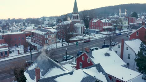 aerial tilt up reveals homes and church in small town community covered in winter snow