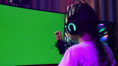 close up back view of asian girl streamer using green screen personal computer. yawning and sleeping, desk illuminated by rgb led strip light