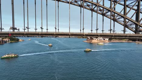 cinematic aerial shot flying under sydney harbour bridge to reveal sydney opera house, sydney landmark at sunset, australia