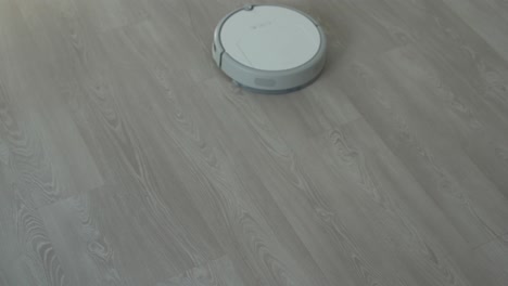 Weißer-Roboterstaubsauger-Auf-Laminatboden,-Der-Staub-Im-Wohnzimmer-Reinigt.-Intelligente-Housekeeping-Technologie.