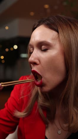 mujer comiendo comida dorada con palillos