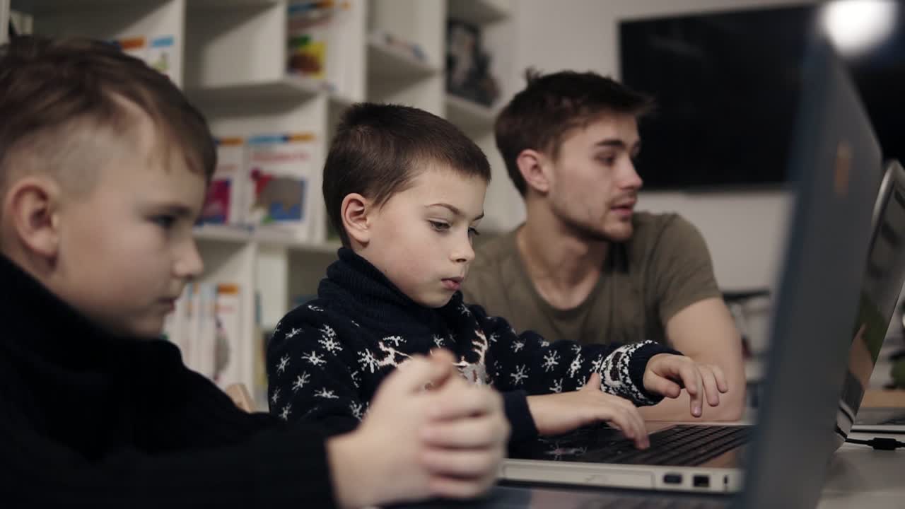 작은 소년은 노트북 키보드에서 무언가를 입력하려고 합니다. 기기를 사용하는 법을 배우고 있습니다. 아이들을 위한 프로그래밍 수업. 교육 과정.