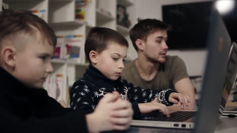 un niño pequeño está tratando de escribir algo en el teclado de una computadora portátil. aprendiendo a usar aparatos. clase de programación para niños. proceso educativo.