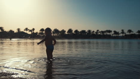 Entzückendes-Kind,-Das-Am-Strand-Im-Wasser-Spaziert.-Süßer-Junge,-Der-Sand-Am-Meer-Nimmt.