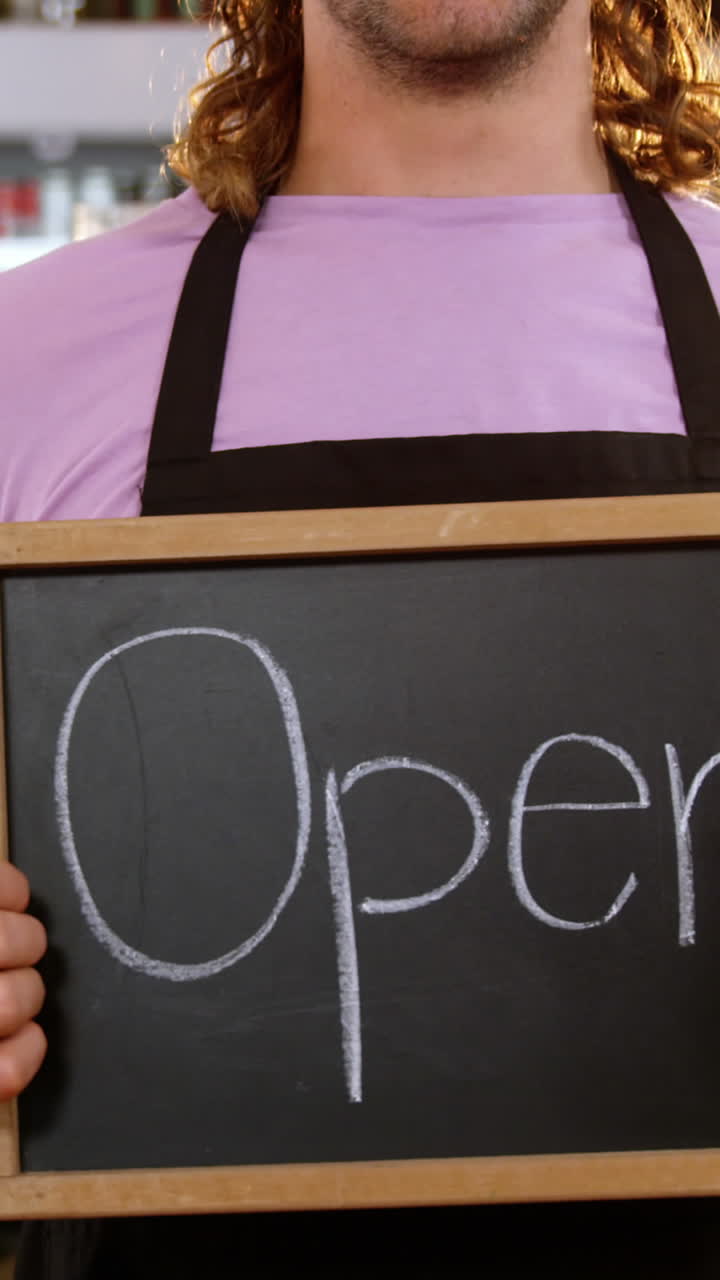 Waiter holding chalkboard with open sign