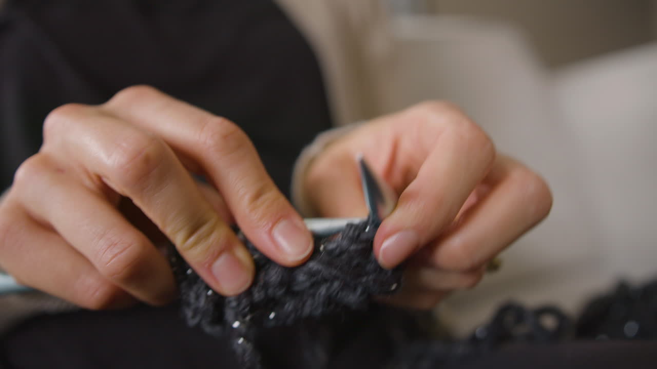 Woman knitting two stitches. Close up, slow motion.
