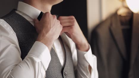 Groom-adjusts-bow-tie,-preparing-to-go-to-the-bride,-businessman-in-white-shirt,-wedding-day