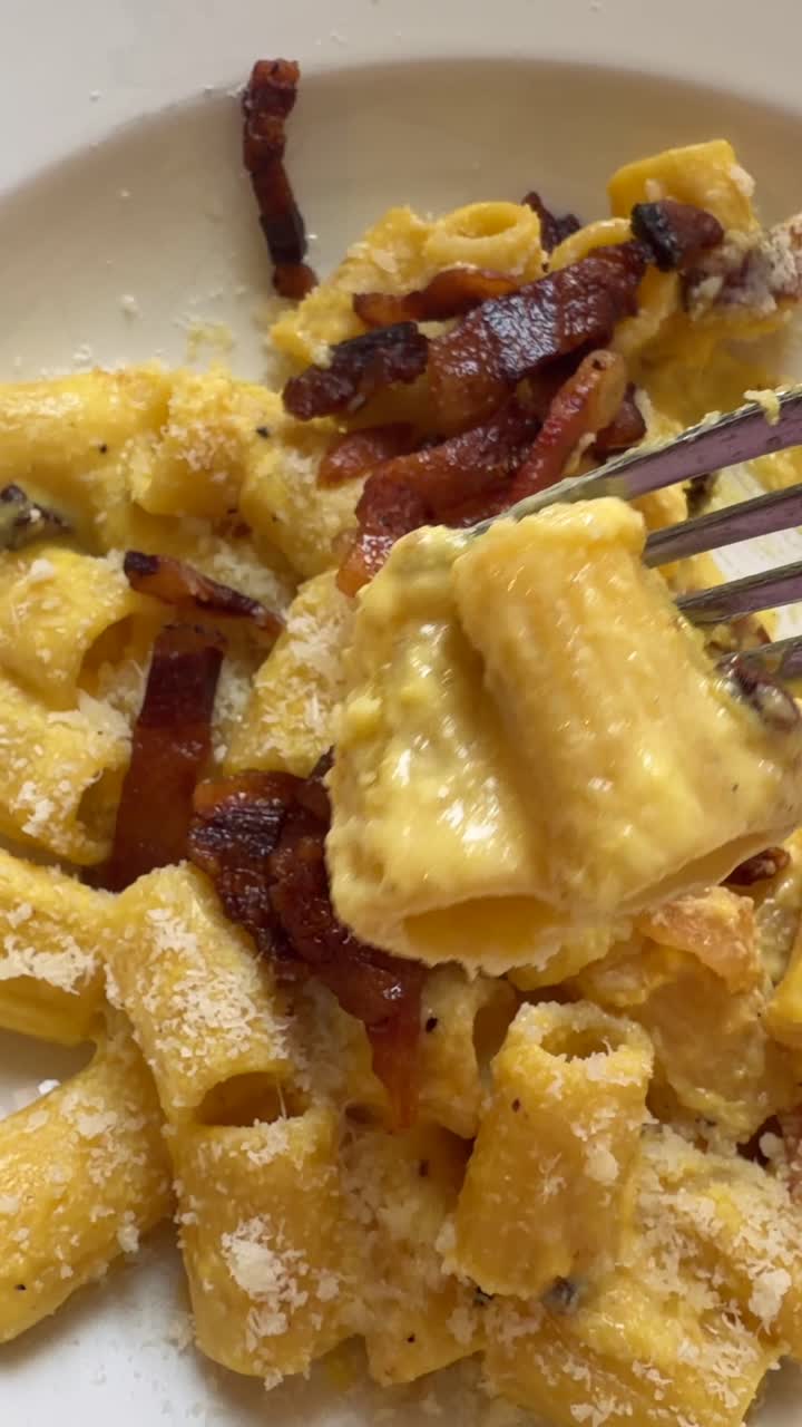 Primo piano di pasta alla carbonara cremosa con guanciale croccante