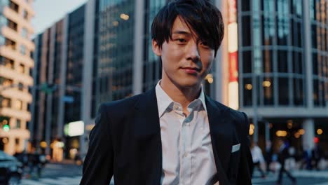 professional asian manager confidently walking through downtown urban street at dusk, projecting corporate success and modern business lifestyle against illuminated city backdrop