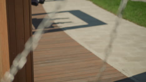 artistic blur of a woman swinging gently, focus on sunlit park atmosphere with multiple people swinging nearby, evoking a leisurely summer day