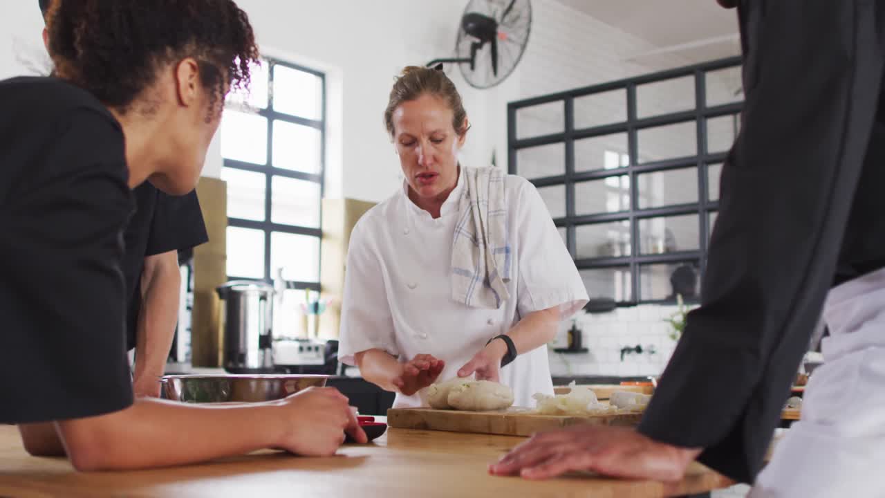 cocinera caucásica que enseña a un grupo diverso usando máscaras faciales