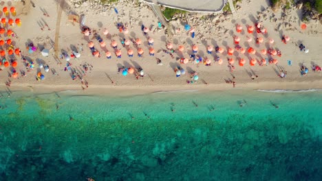 descending top down view clear emerald sea of petani beach, colorful beach umbrellas