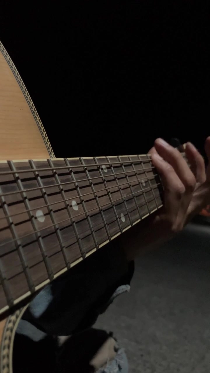 Ripresa verticale in 4K ravvicinata che si concentra sul manico, sulla tastiera e sulle corde di una chitarra acustica suonata da un uomo di notte. B-roll di una performance musicale suggestiva in condizioni di scarsa illuminazione per contenuti artistici estetici.