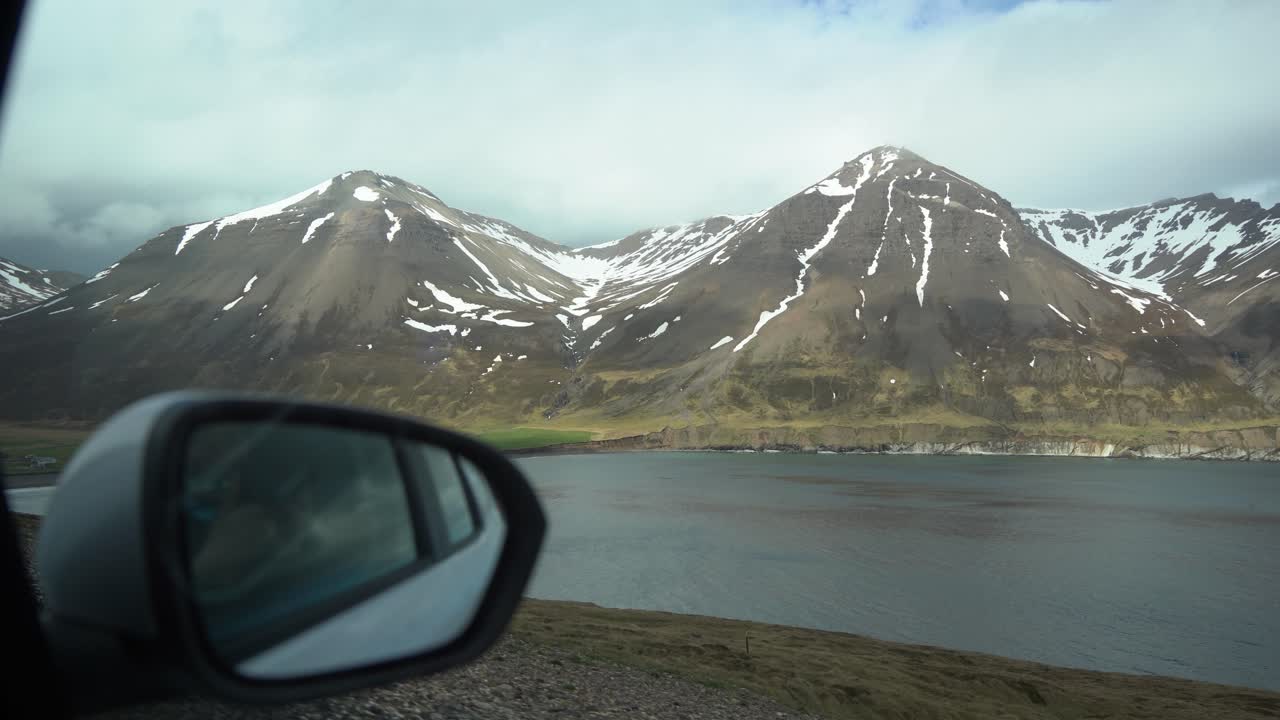 POV shot from a car window driving through Eastfjords in Iceland, surrounded by mountains